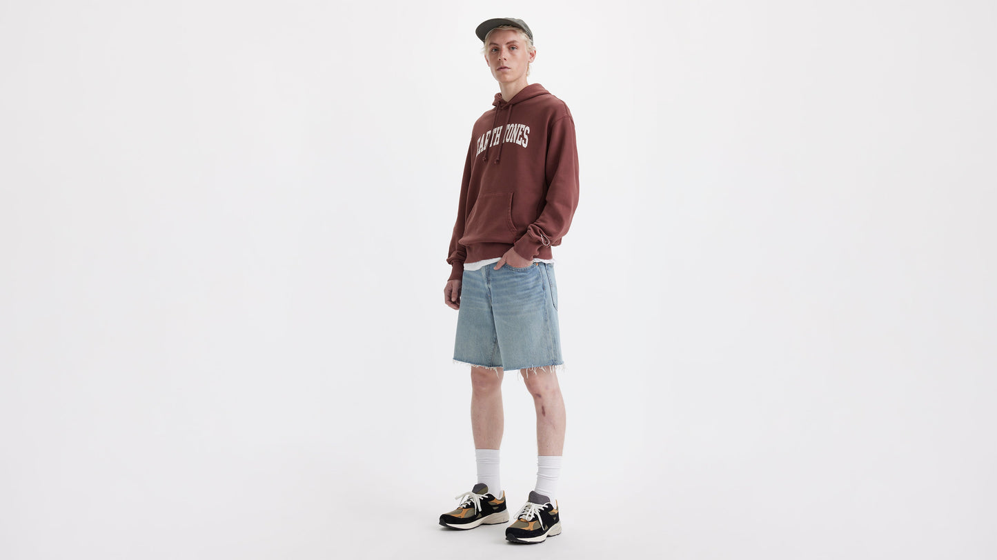 Front view of man in Levi’s 468 loose Shorts with maroon hoodie, cap, & sneakers