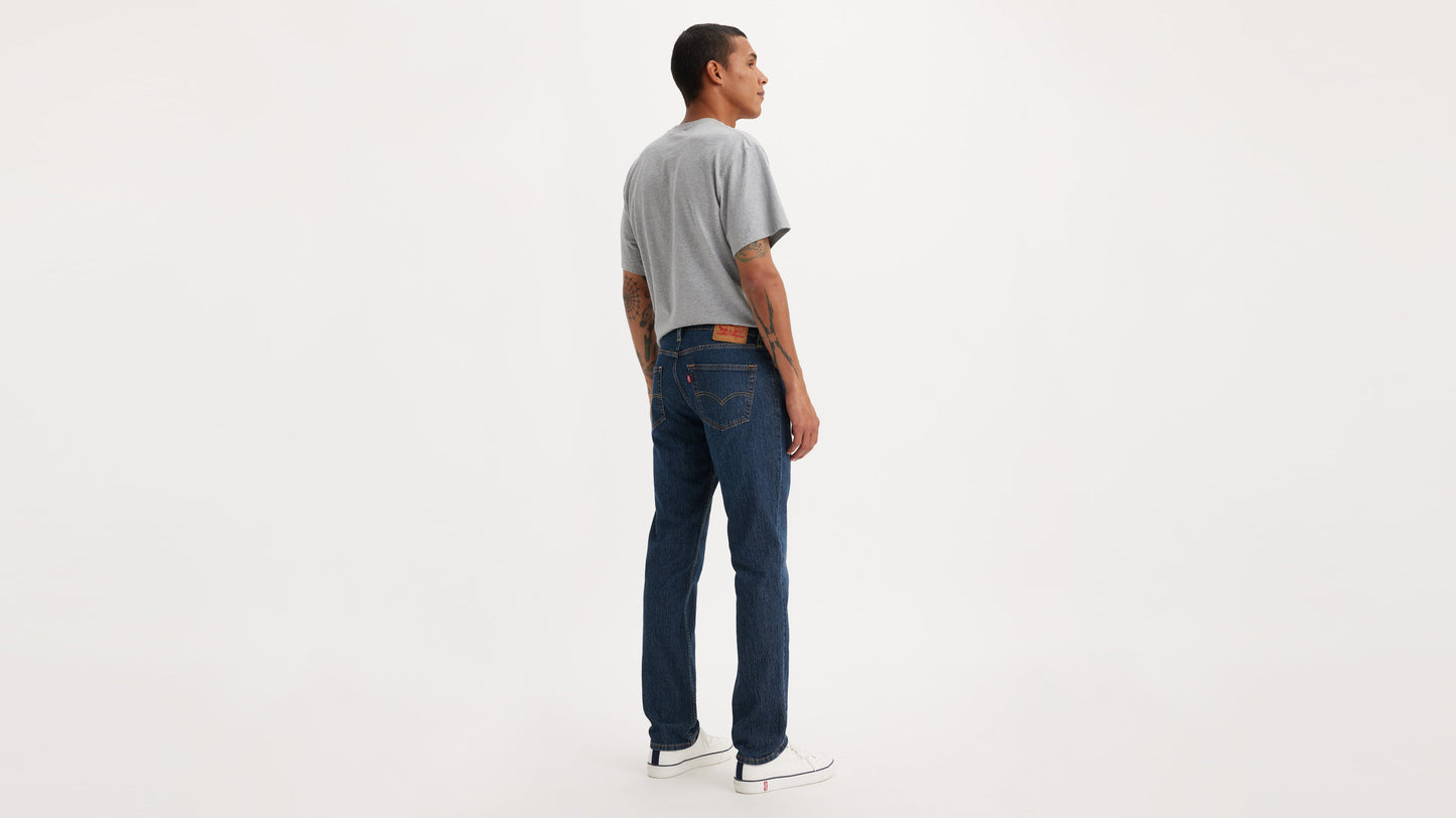 Back view of man in Levi’s 511 Slim Jeans in dark blue, grey tee, & white sneakers