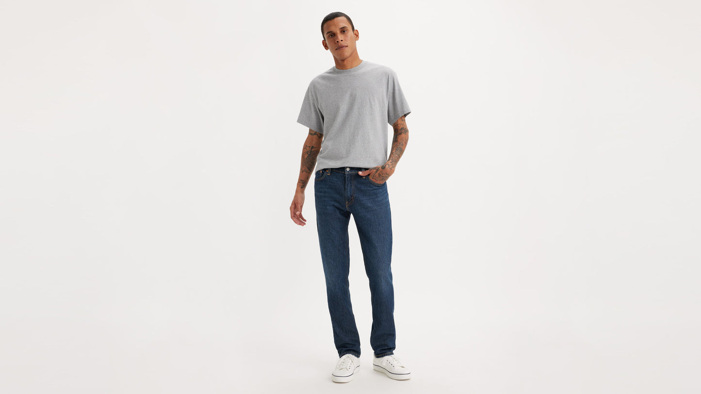 Front view of man in dark indigo Levi’s 511 slim jeans, grey tee & white shoes