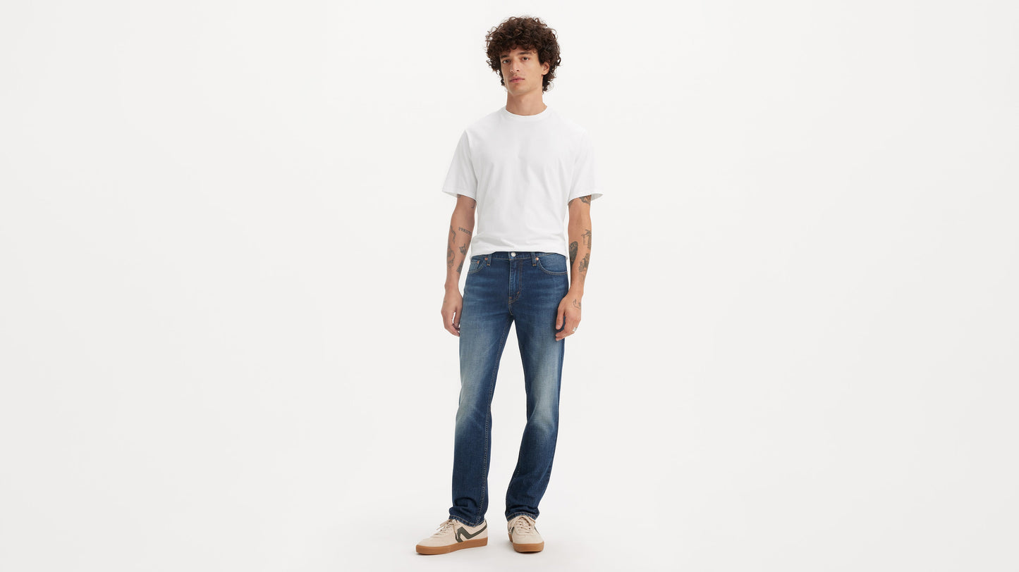 Front view of a man wearing mid-wash Levi’s 511 jeans with a white tee & sneakers