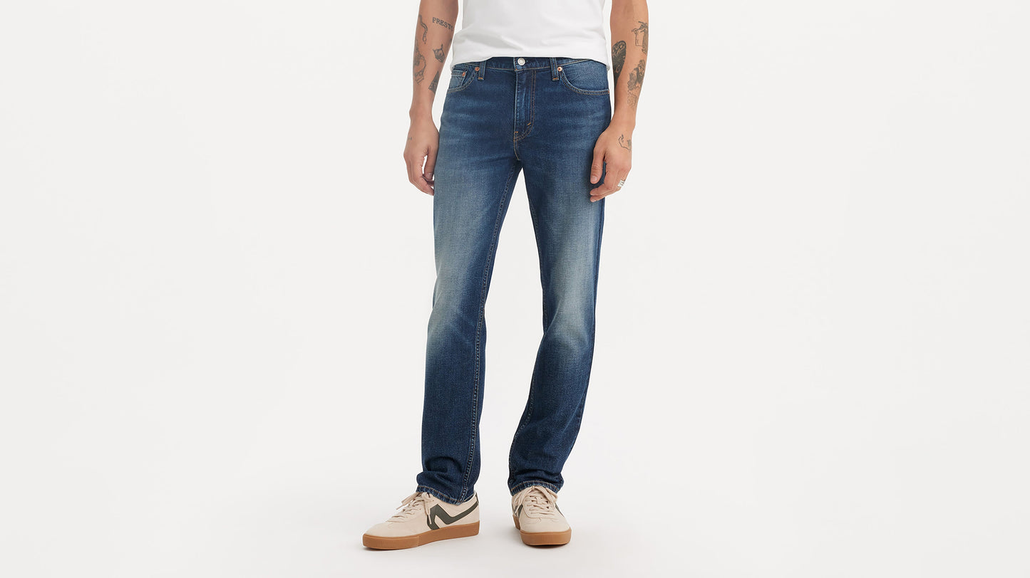 Cropped-view of a man wearing mid-wash Levi’s 511 jeans paired with beige sneakers