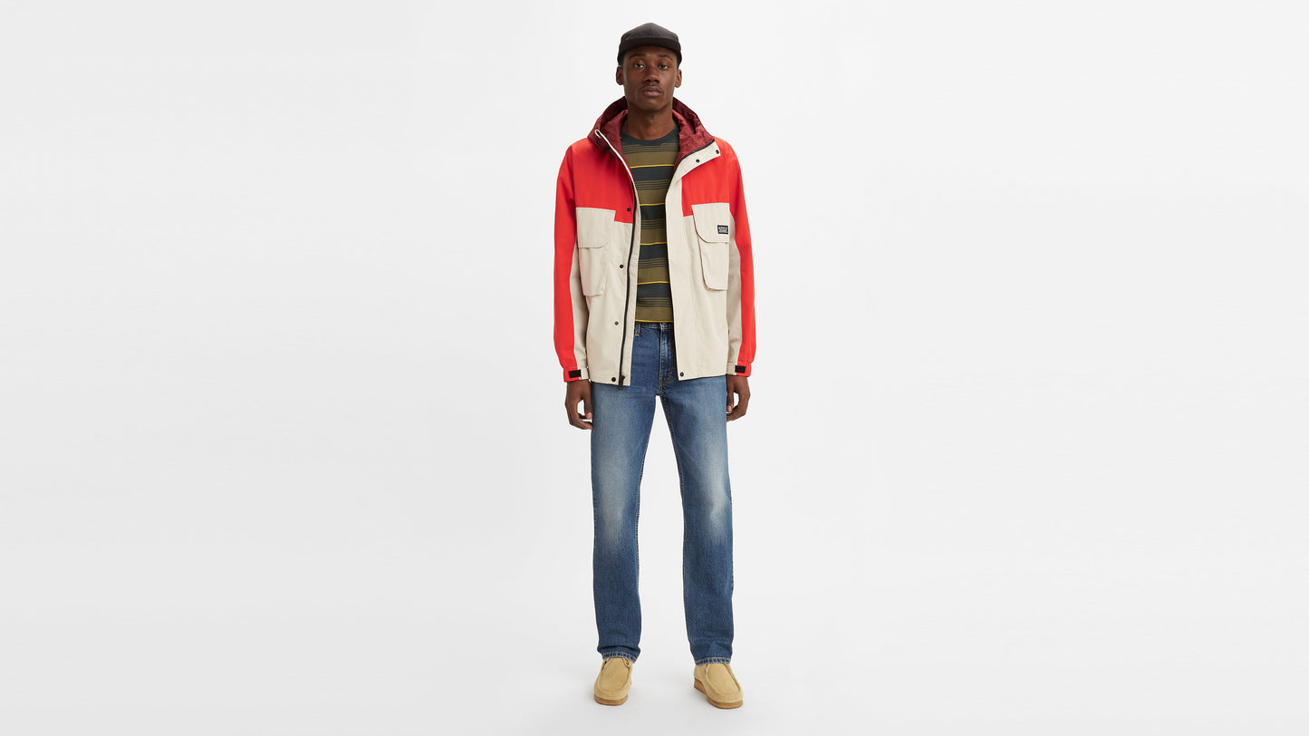 Front view of a man wearing mid-wash Levi’s 514 jeans styled with a red & beige jacket