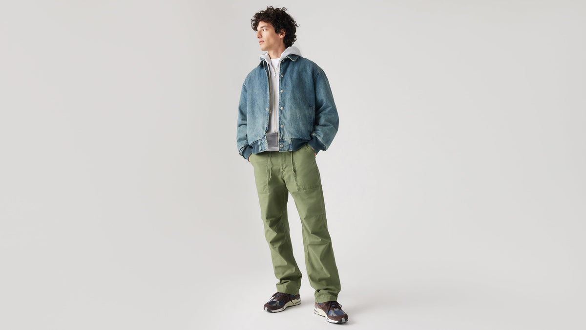 Man in denim jacket, hoodie, green Loose Straight Surplus Pants, & sneakers