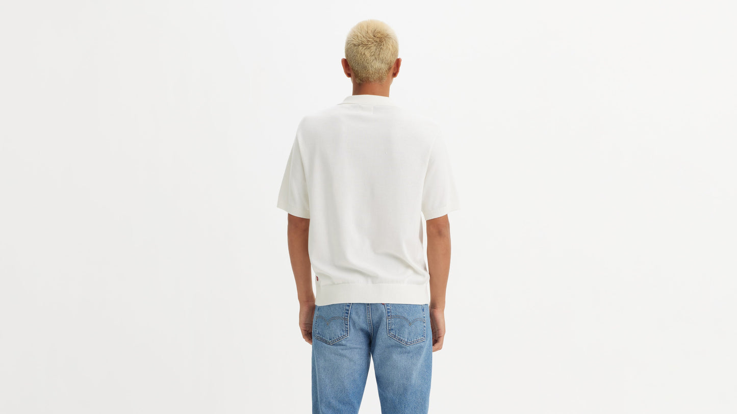 Model in white Levi's knit polo shirt & blue jeans, back view