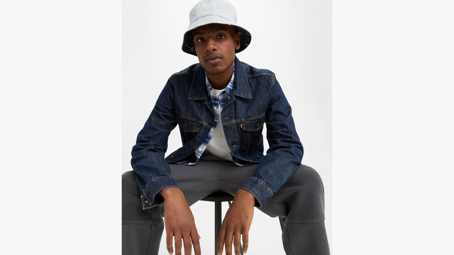 Model in Levi’s men’s Trucker Jacket in dark wash, seated front view