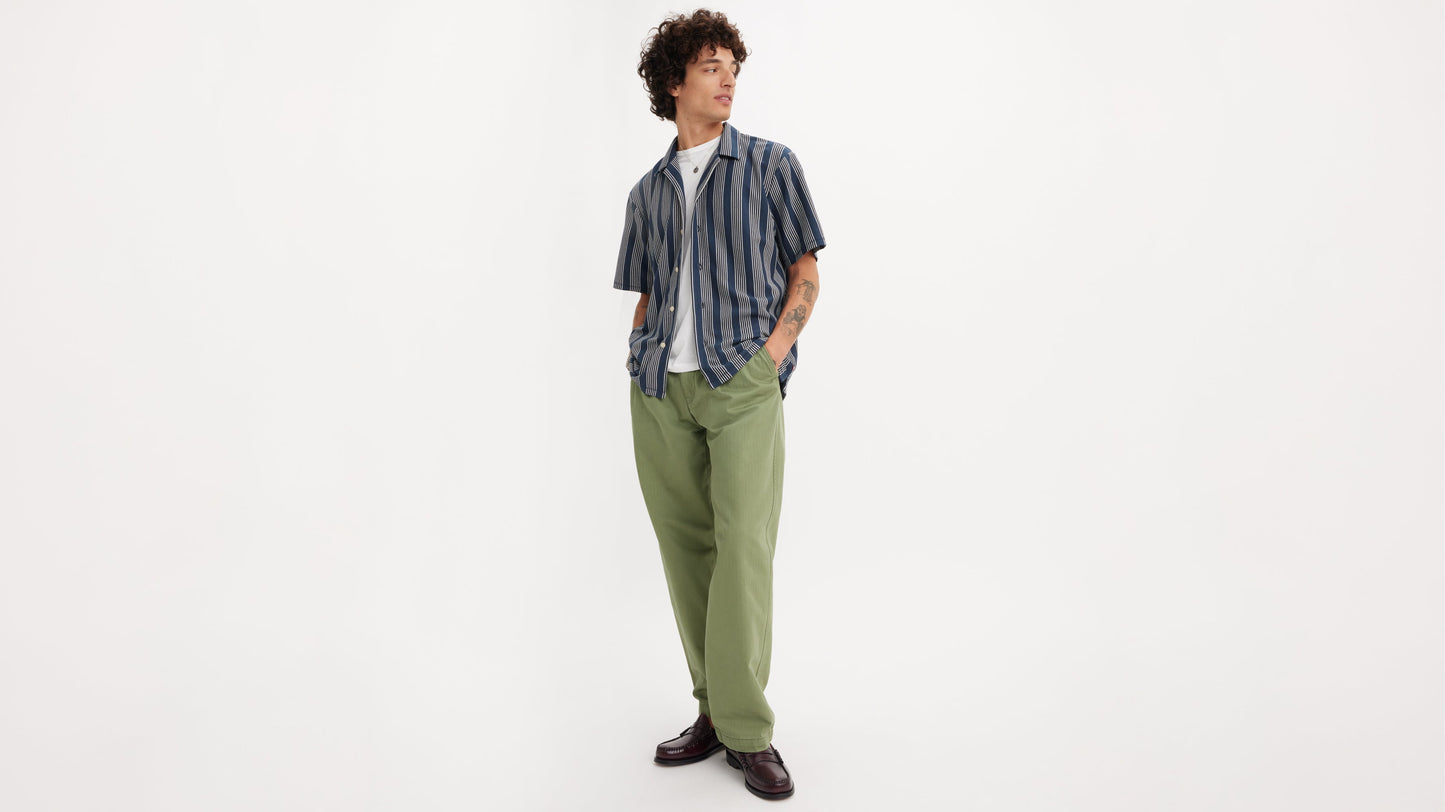 Man in casual striped shirt, green chino loose pants, and burgundy shoes looks left