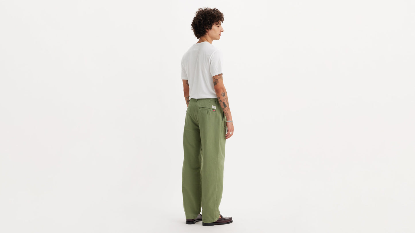 Rear angle of model in chino loose straight green pants and plain white tee shirt