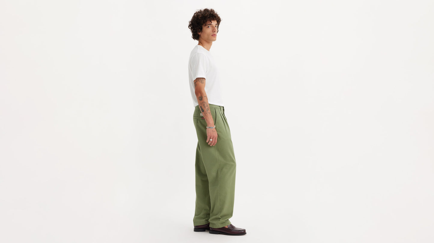 Side view of model in chino loose straight green pants and plain white t-shirt