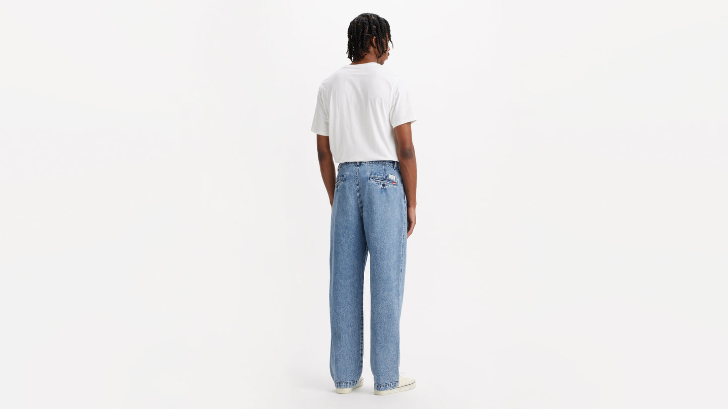 Back view of man in chino loose straight pants and plain tee, hands by his sides