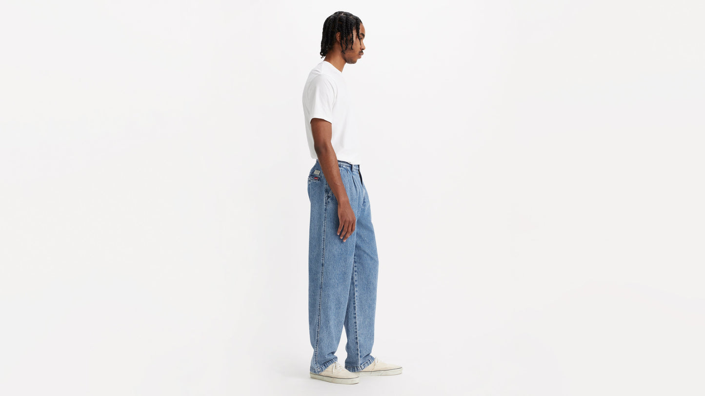 Side view of man in chino loose straight pants and plain tee, hands by his sides