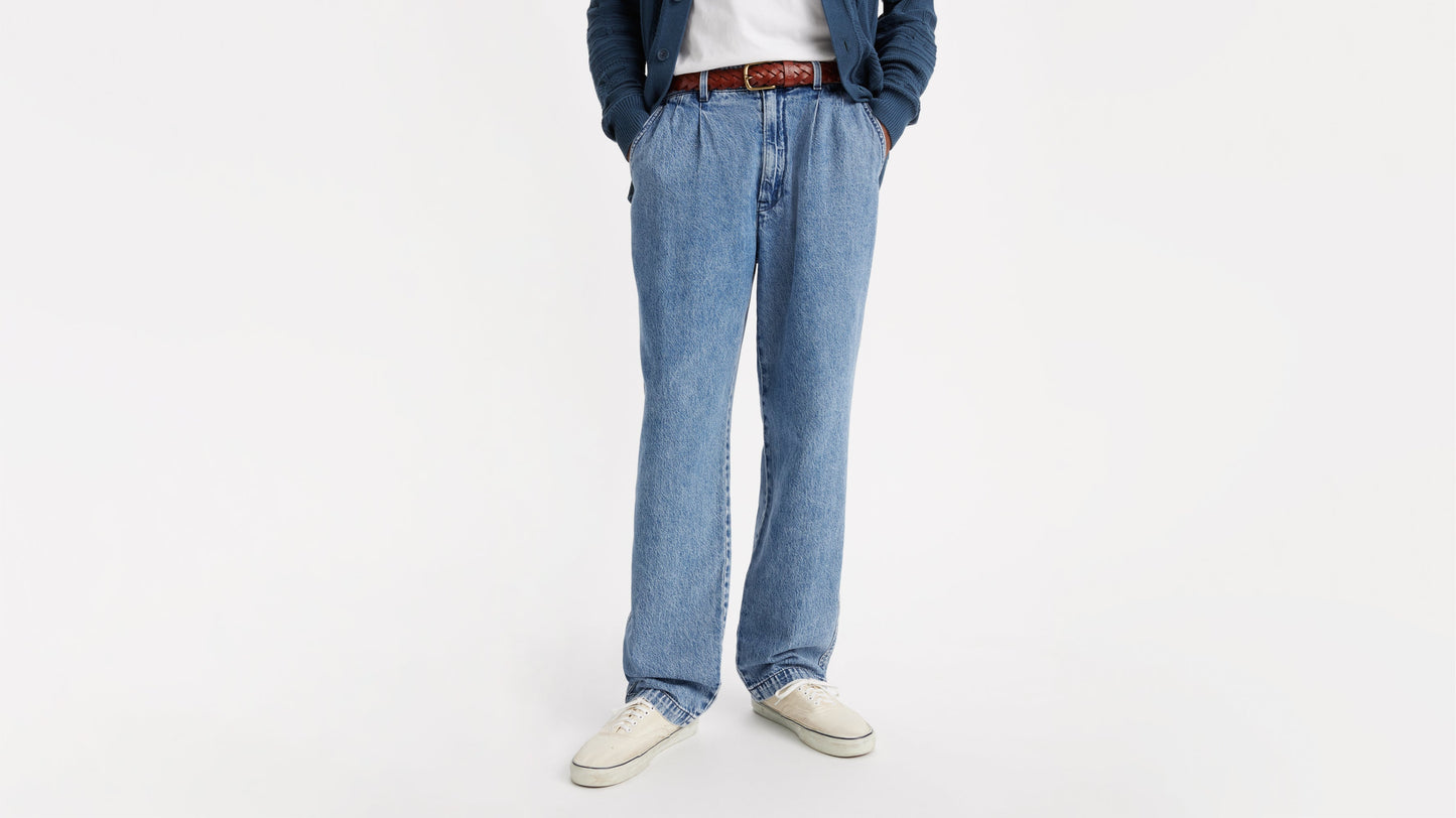 Close-up of blue chino loose straight pants, brown belt, and off-white canvas shoes