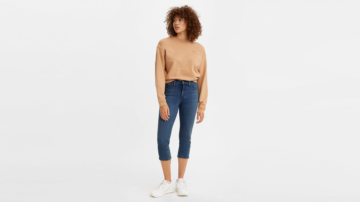 Woman in dark blue Levi’s capri jeans and tan sweatshirt