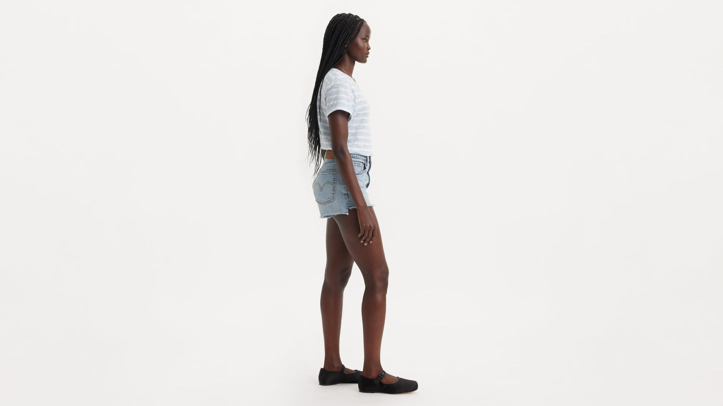 Side view of a model in Levi's 501 Shorts in light blue with striped tee and black flats