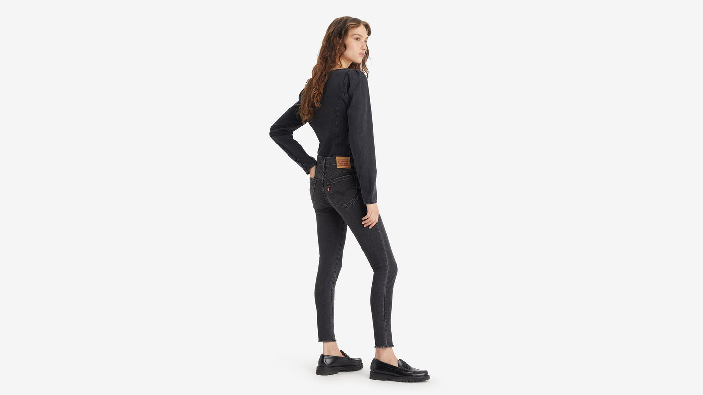 Woman in back-side view wearing Levi's 710 Mid-Rise Super Skinny Jeans in faded black