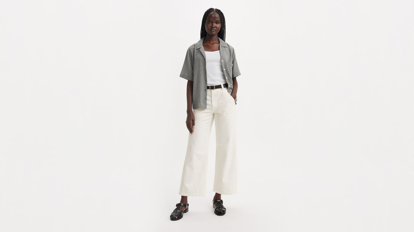 Front view of woman in off-white Levi’s carpenter jeans, tank top, & check shirt