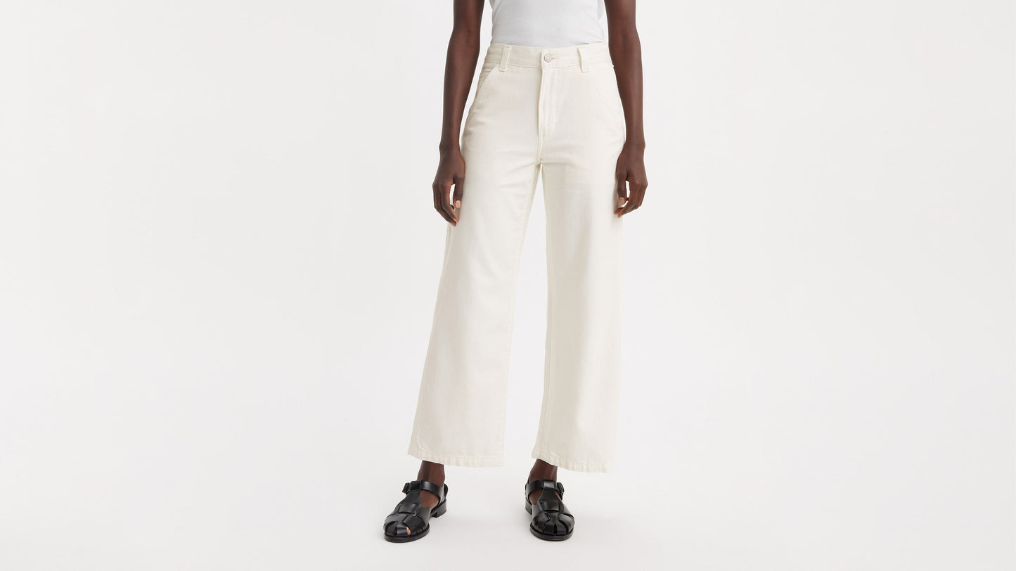 Cropped front view of a woman in off-white Levi’s carpenter jeans & black sandals