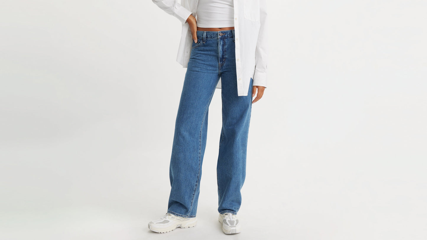 Half-body shot of a woman in Levi's Baggy Jeans, white long sleeve, & sneakers