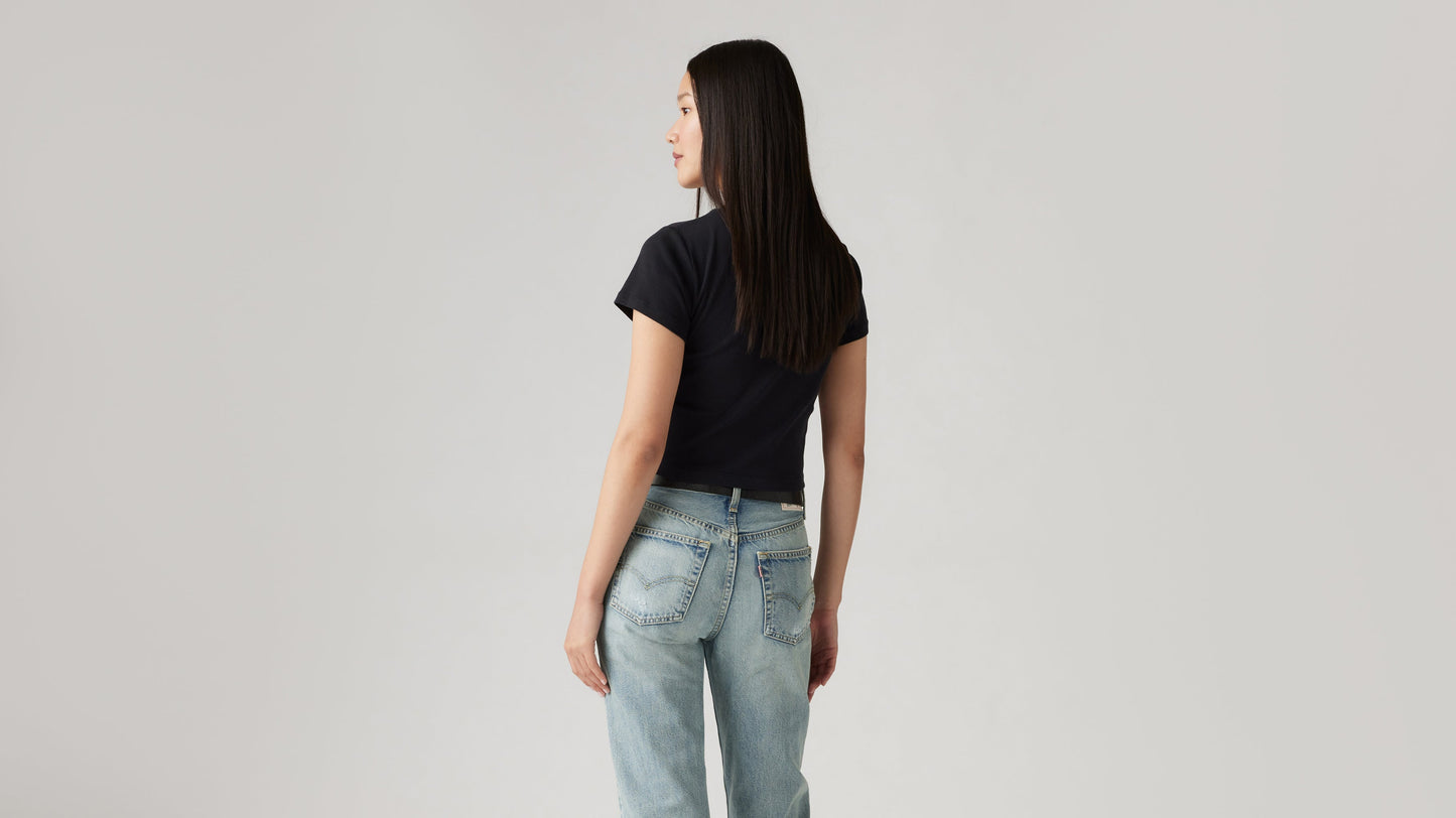 Woman in light Levi's jeans and black cropped tee, back view