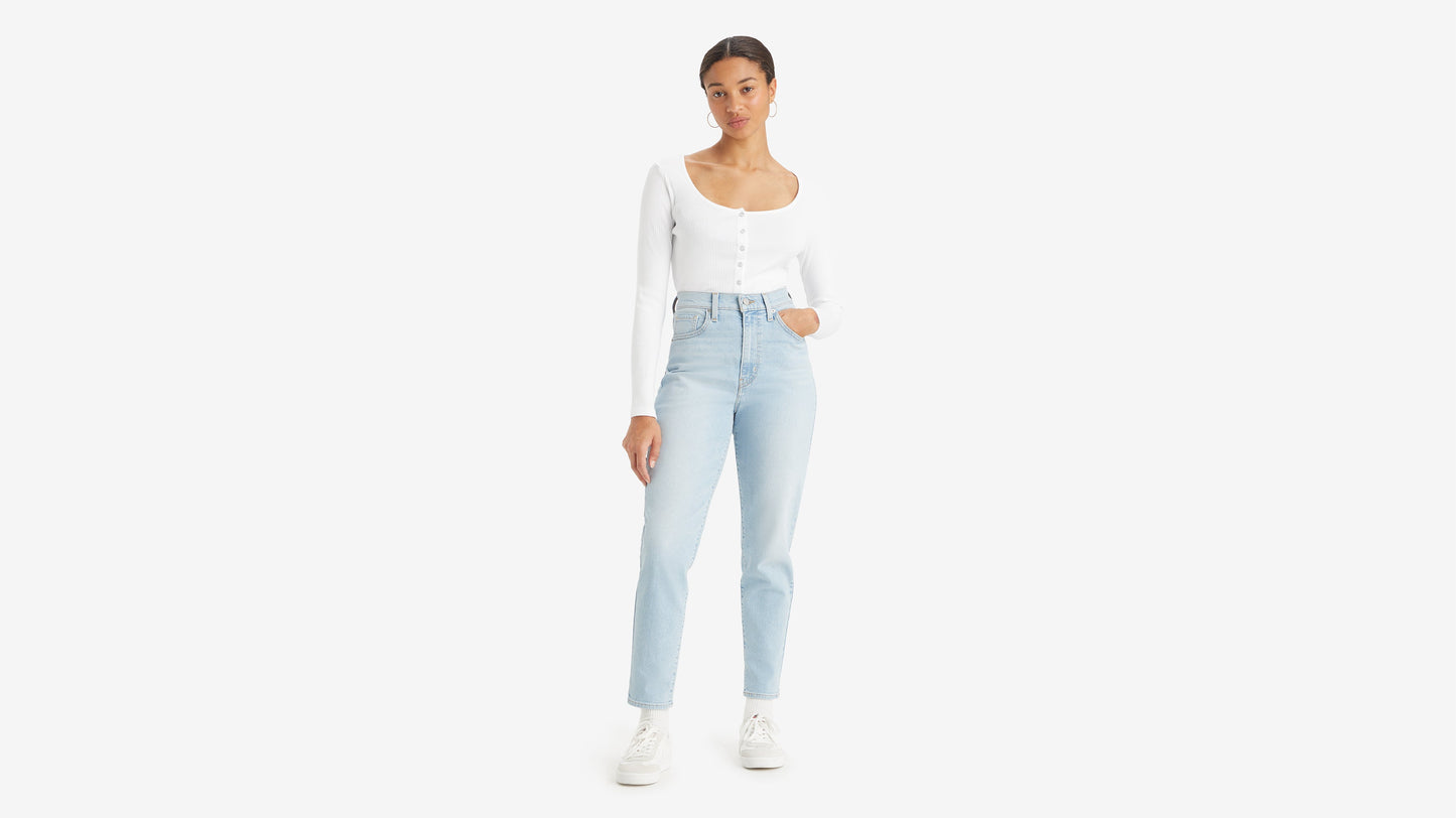 Front view of a woman in white top tucked in high-waisted mom jeans