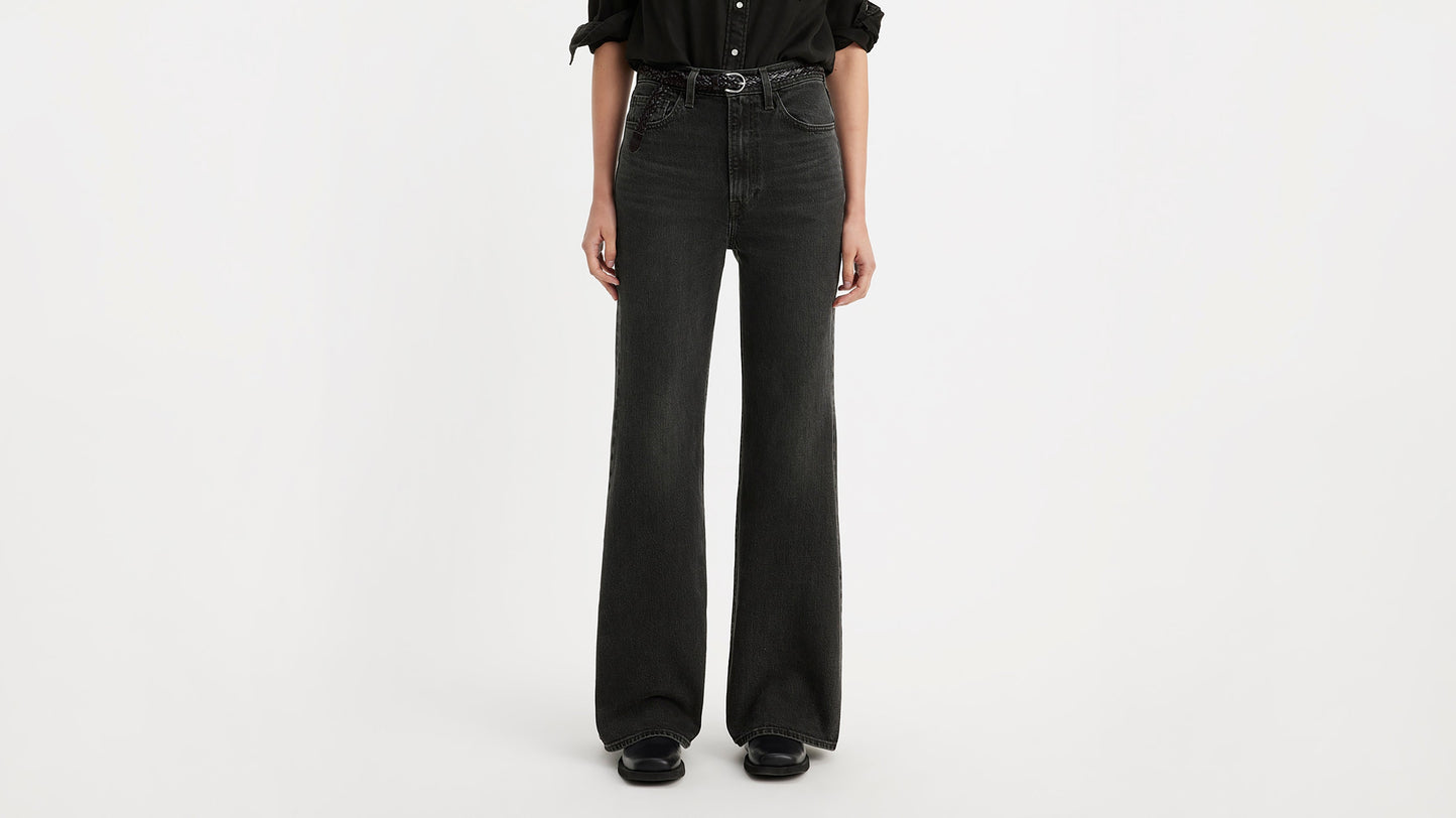 Half-body shot of a woman in black Levi's ribcage bell jeans & black shoes