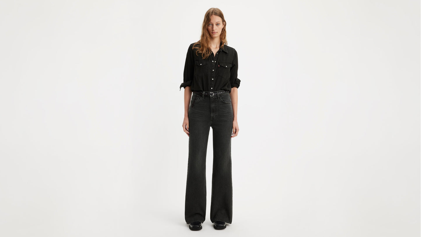 Model in a black shirt tucked into Levi's ribcage bell jeans with black belt