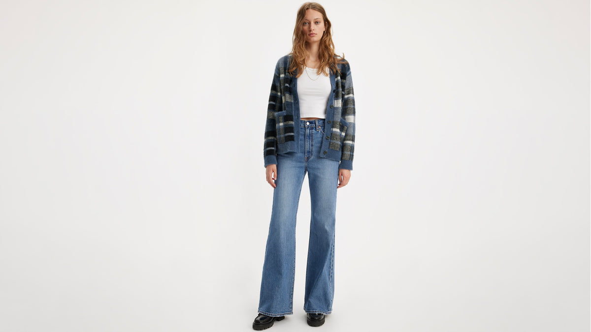 Model in Levi's Bell Jeans in blue, white tank top, & blue plaid cardigan