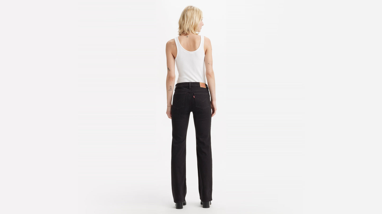 Back view of woman in Levi's Superlow Bootcut Jeans with white tank and boots
