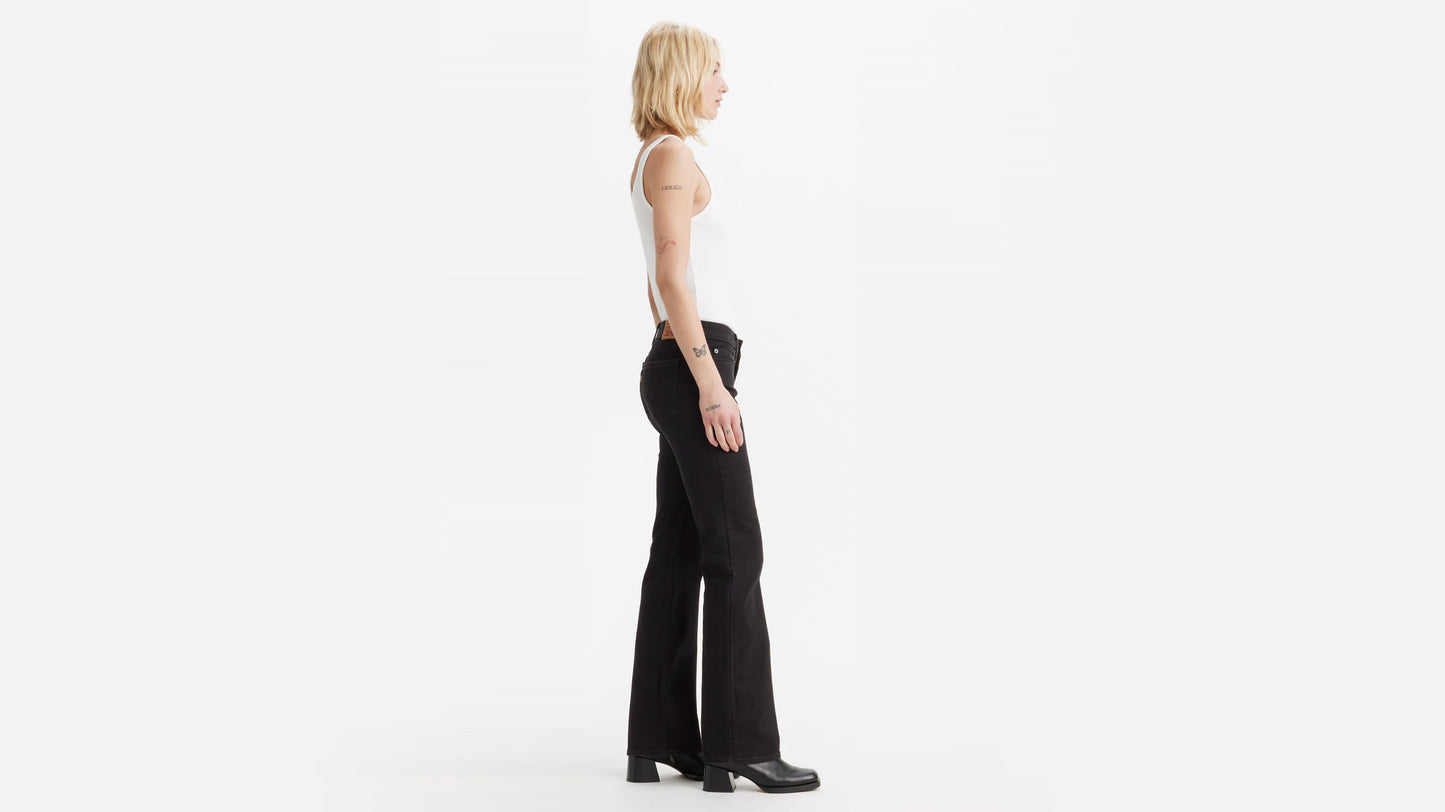 Side view of woman in Levi's Superlow Bootcut Jeans with white tank and boots