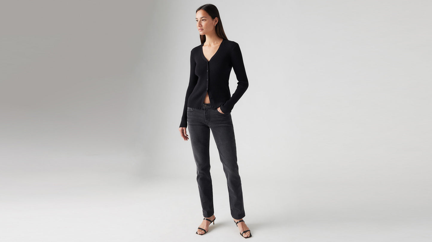 Front view of a woman in a black cardigan, black Skinny jeans, & strappy heels