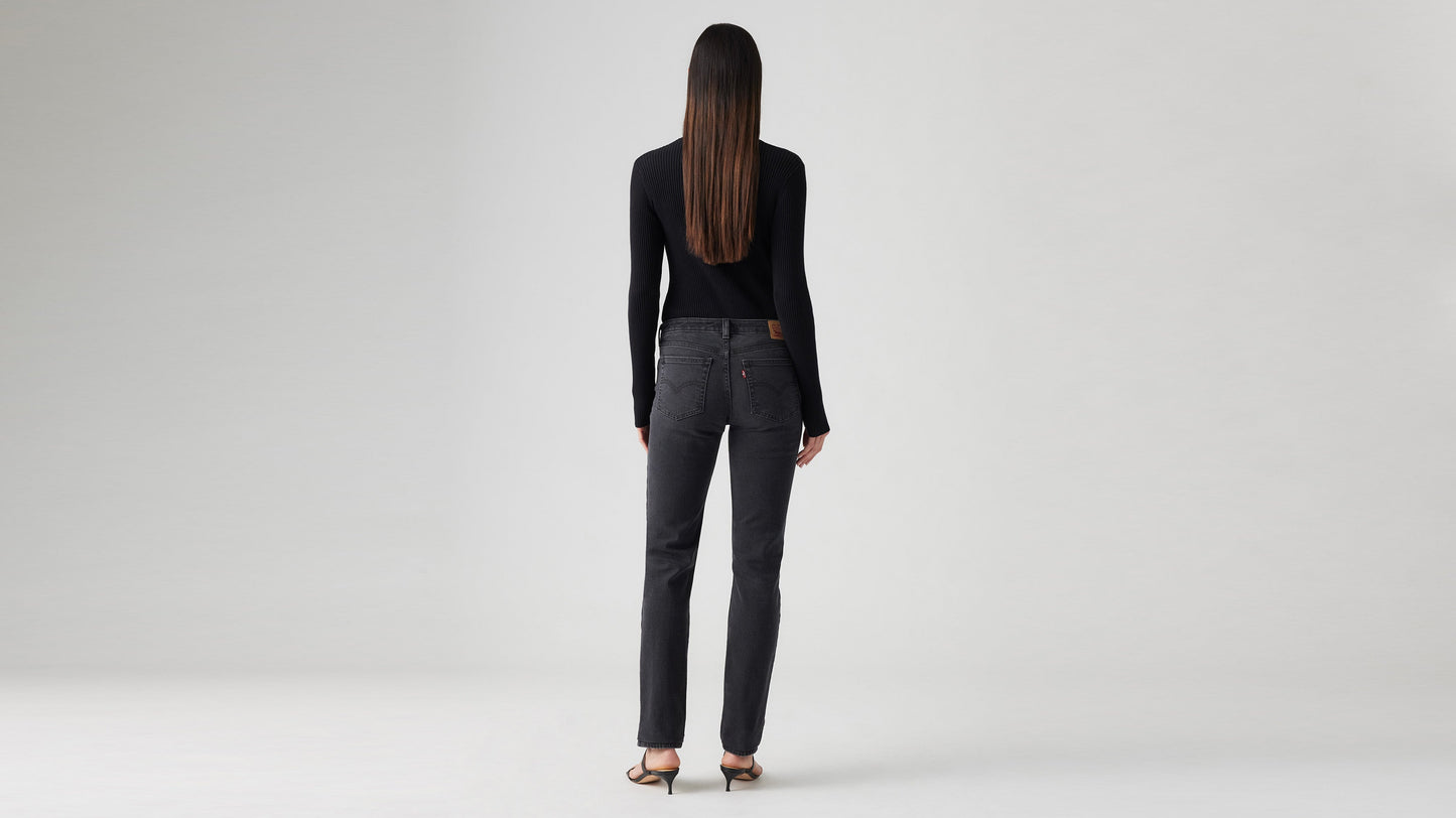 Woman in a black cardigan, black Skinny jeans, & strappy heels, back view