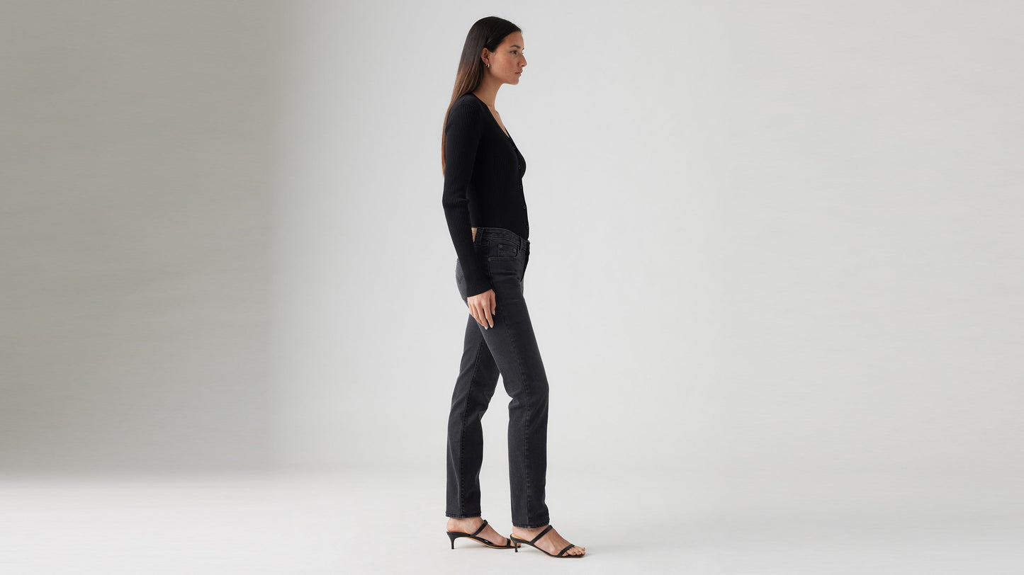 Side view of a woman in black cardigan, black Skinny jeans, & strappy heels