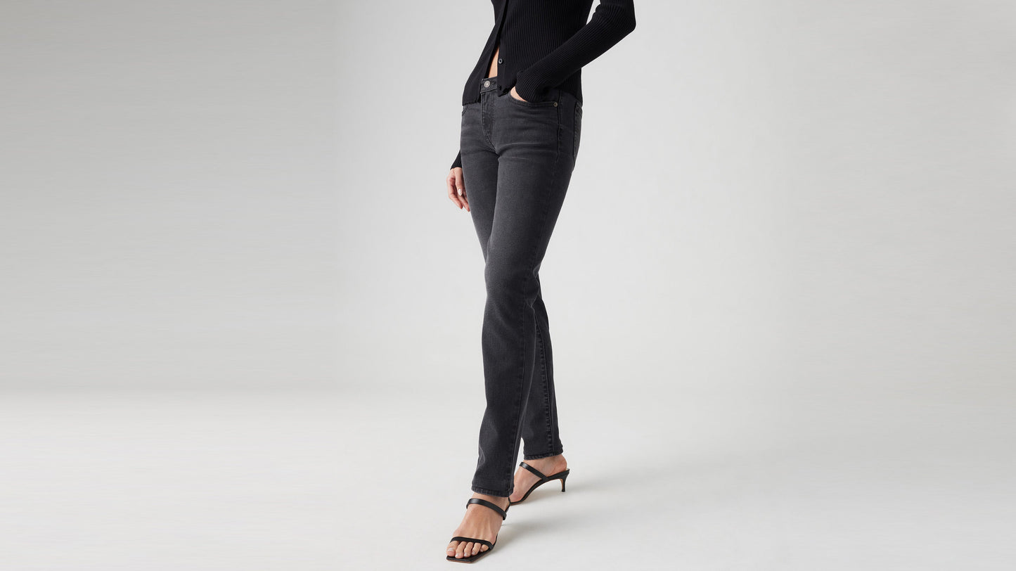Cropped front view of model in black Levi’s superlow skinny jeans, one hand in pocket