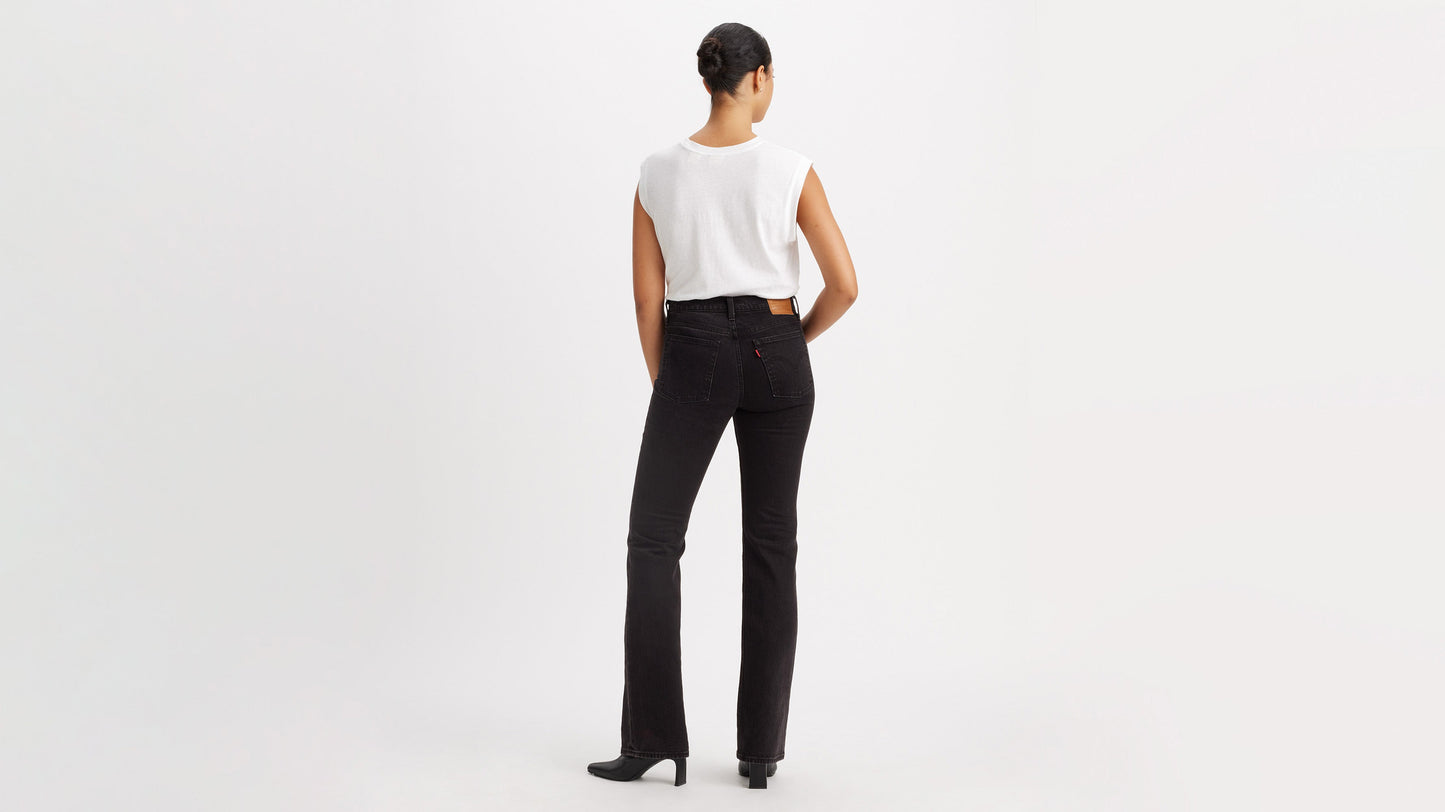 Back view of a woman in white top, black Levi's Wedgie Jeans, & boots