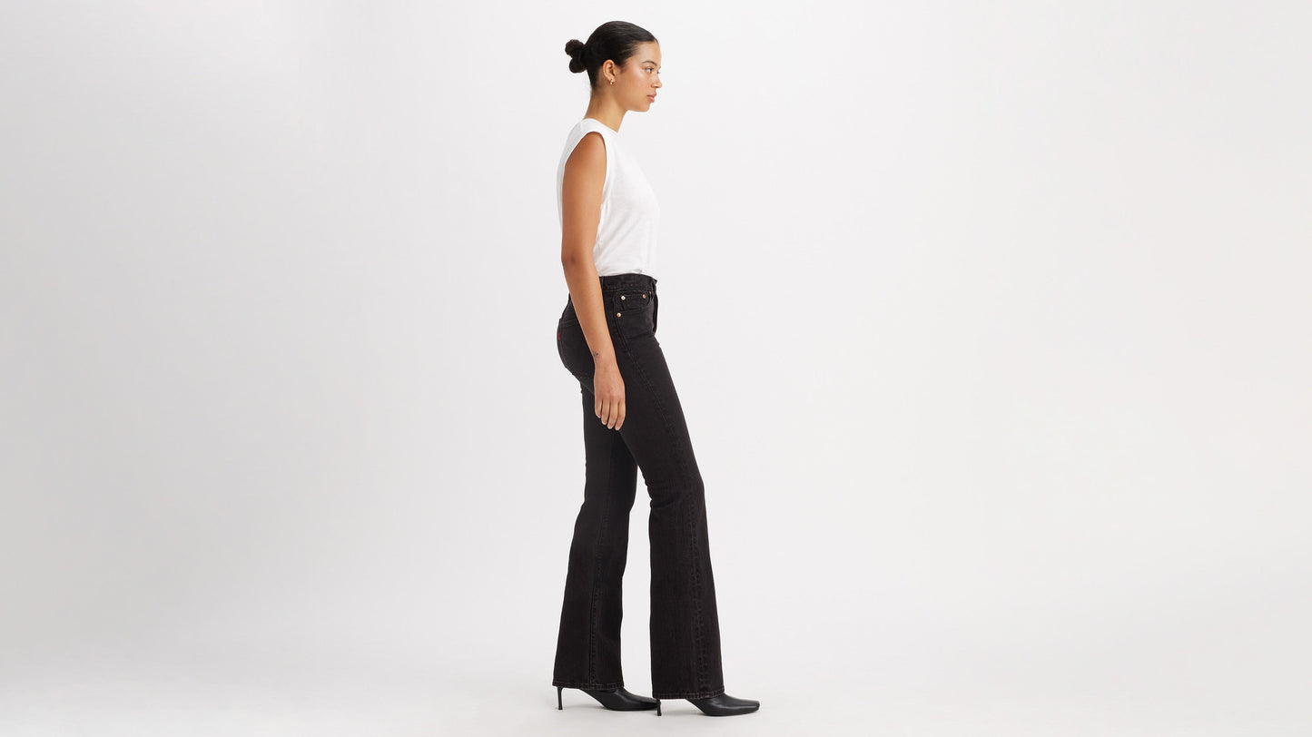 Side view of a woman in white top, black Levi's Wedgie Jeans, & boots