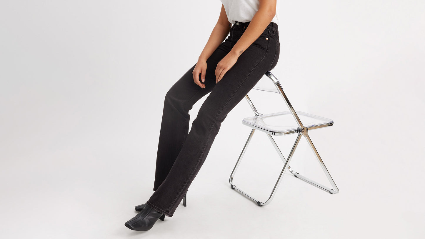 Cropped side view of a woman in black Levi's Wedgie Jeans, & boots, worn seated