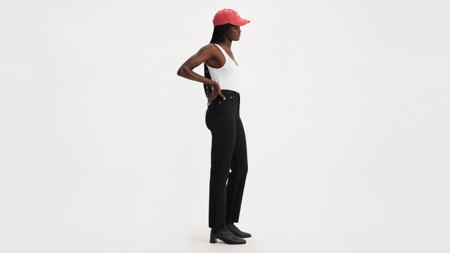 Side profile of woman in black Wedgie Straight jeans and red cap