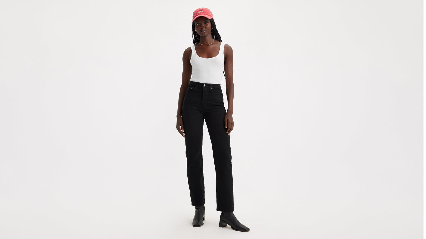 Woman in black Wedgie jeans, white tank top, and a red baseball cap