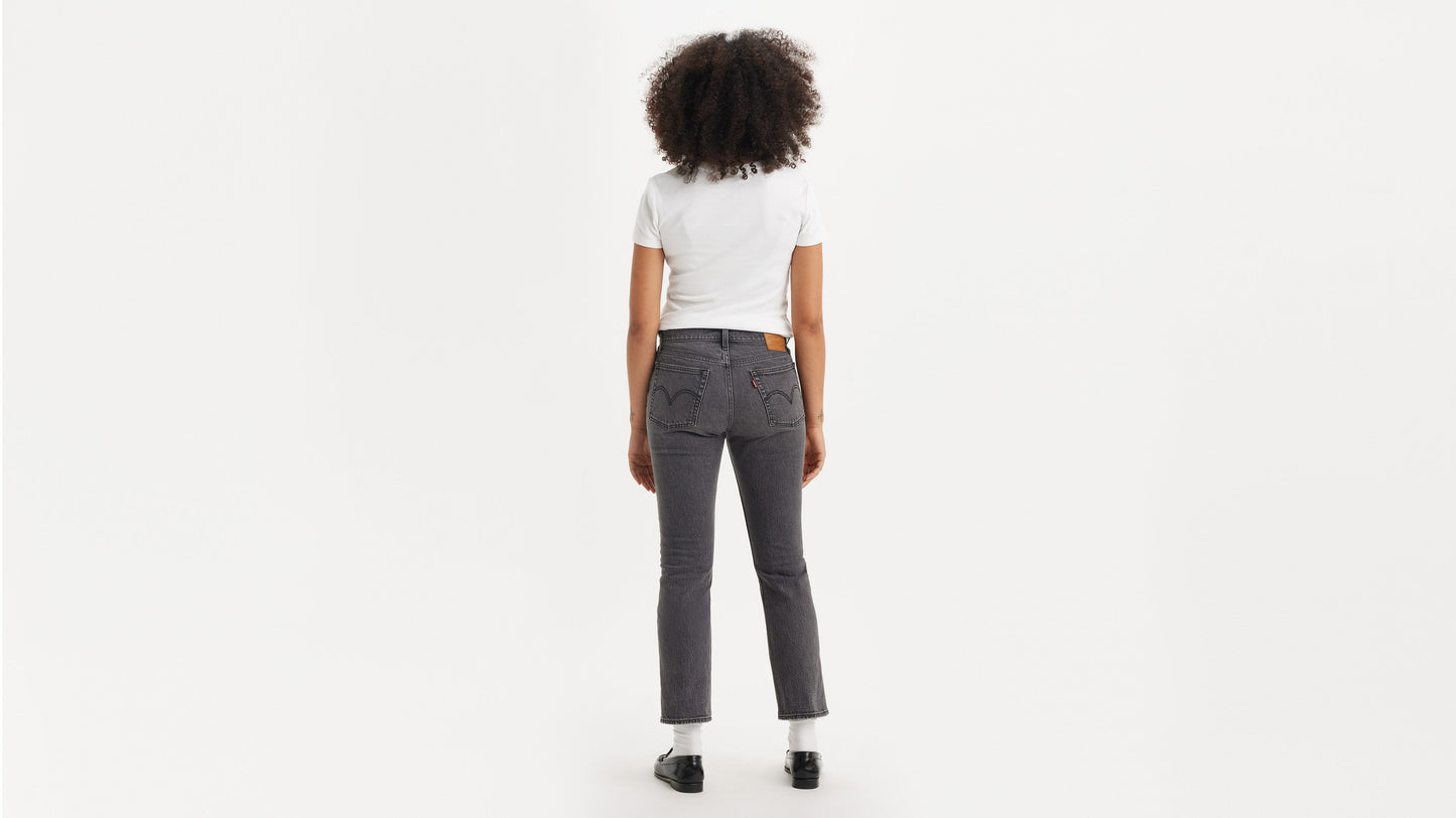 Woman in black loafers, grey wedgie jeans, & white tee, back view