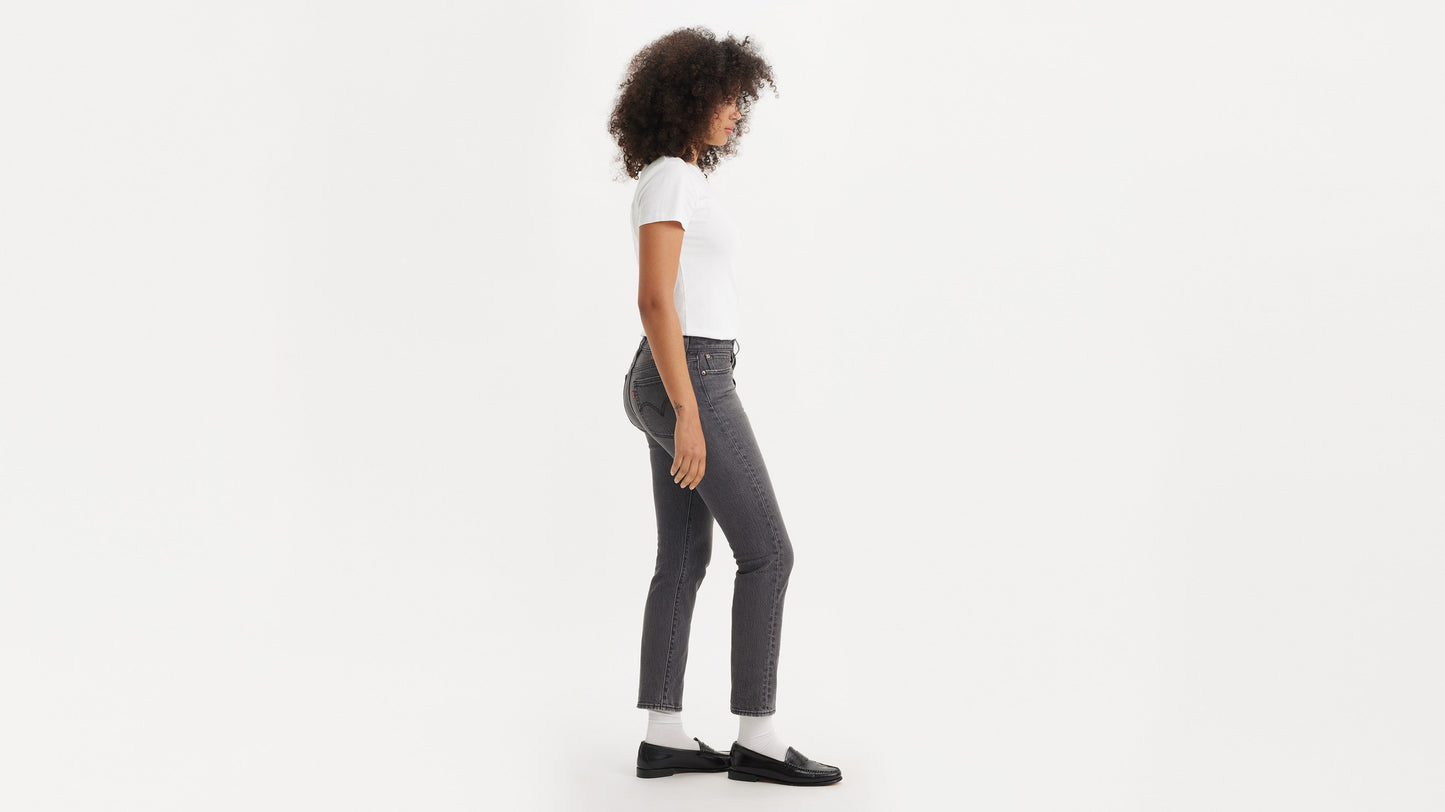 Side view of a woman in black loafers, grey wedgie jeans, & white tee
