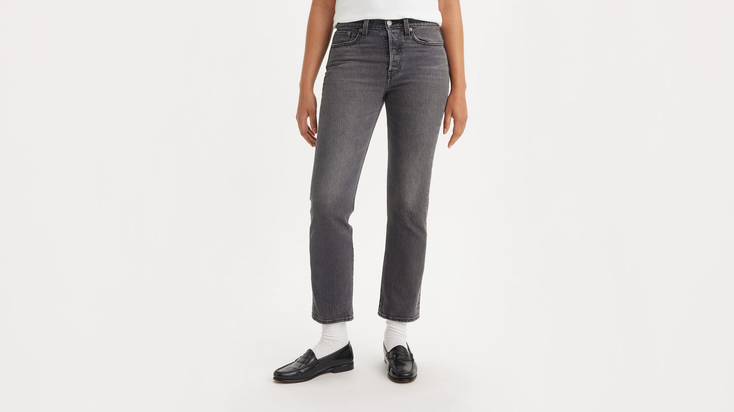 Half-body shot of a woman in black loafers & grey straight jeans