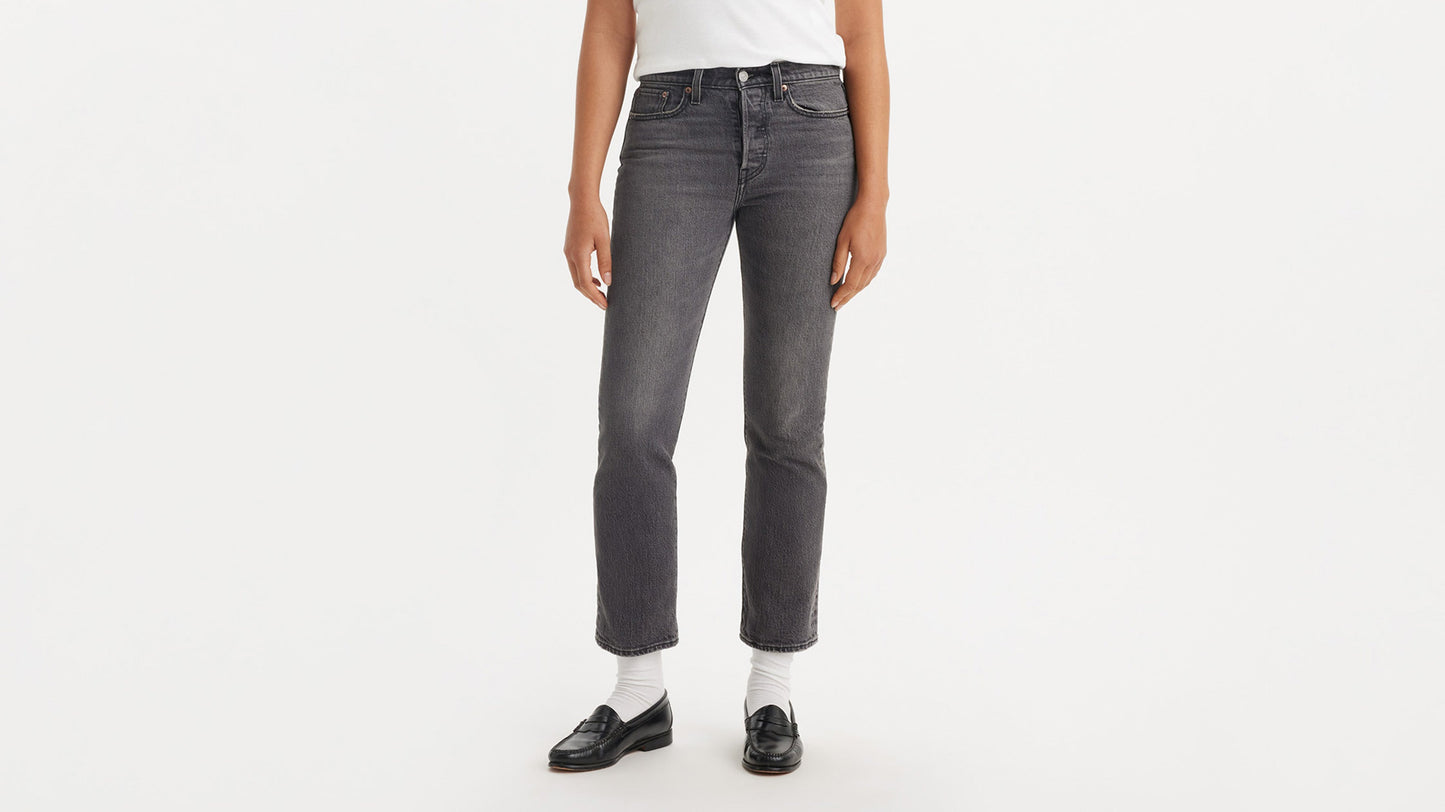 Cropped front view of a woman in black loafers & grey straight jeans