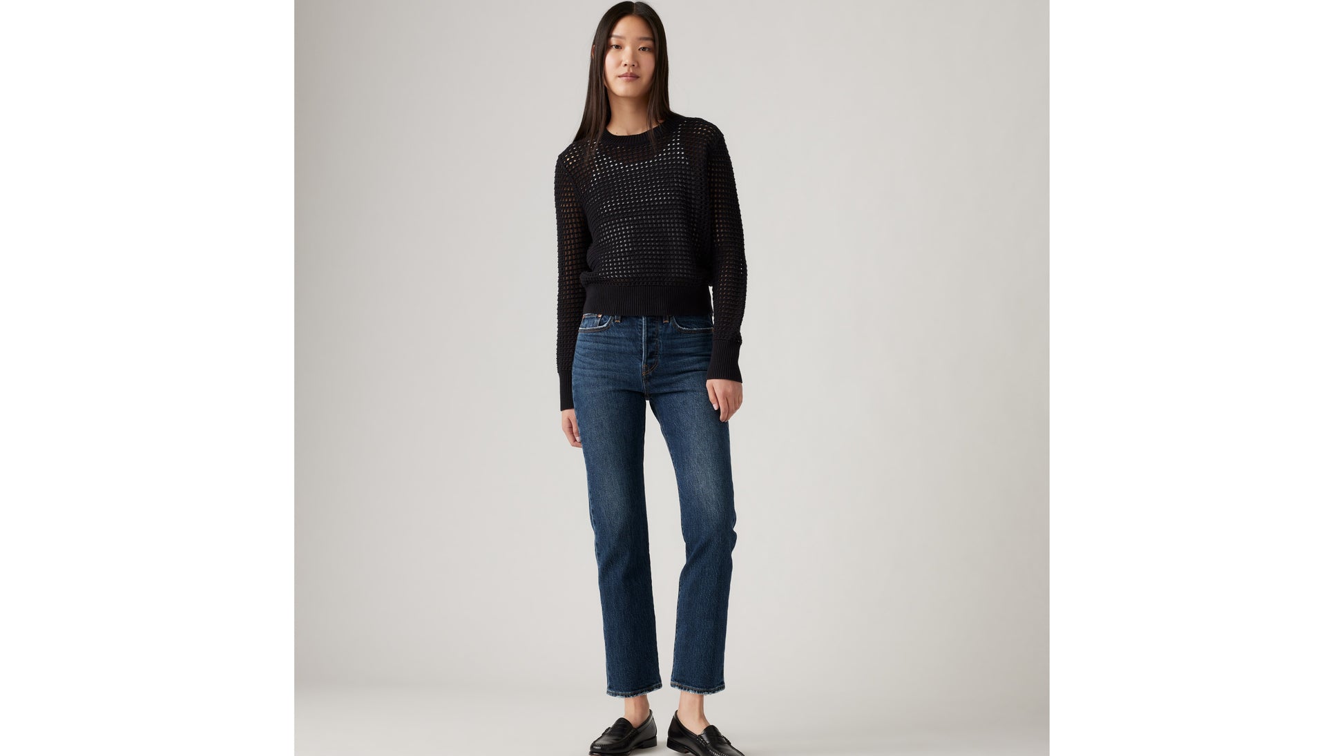 Model in Levi's black mesh sweater and blue jeans