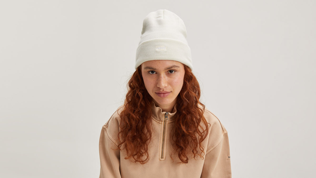Model wearing ivory knit hat and beige Levi’s sweatshirt