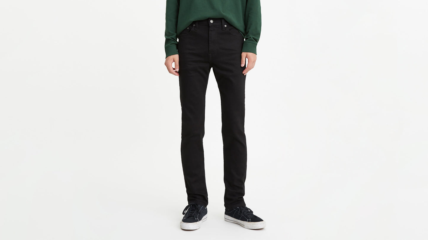 Cropped front view of a man in black skinny jeans with green sweatshirt & sneakers
