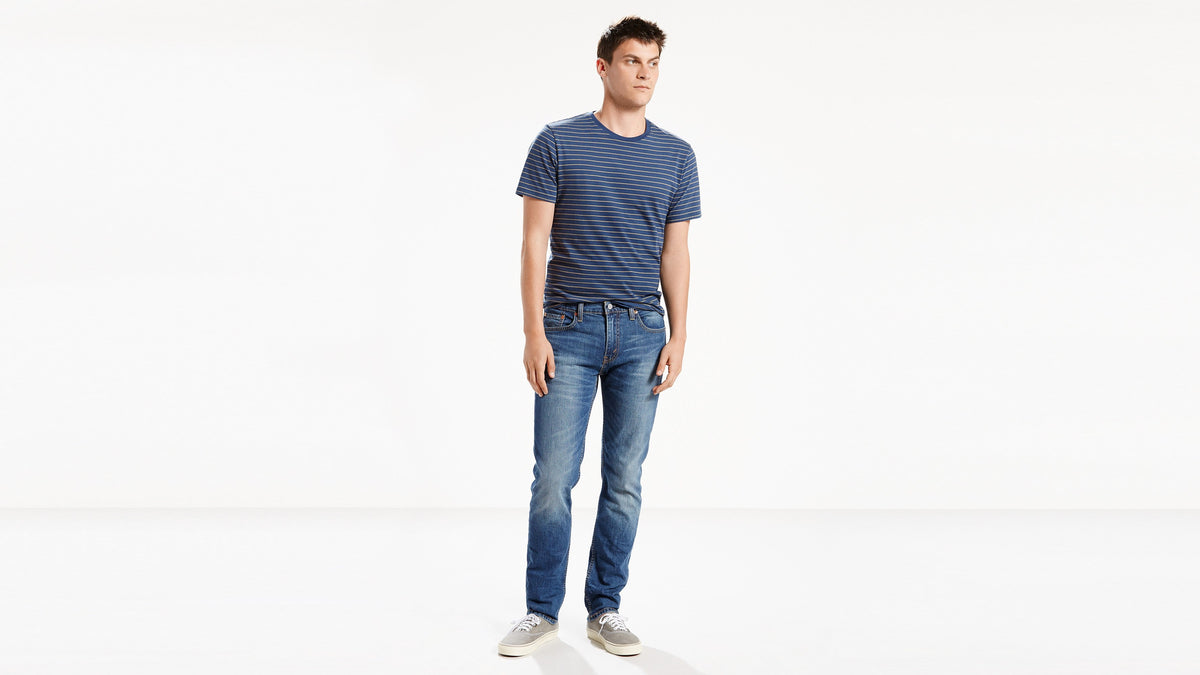 Man in mid-blue Levi’s slim-fit jeans and striped tee