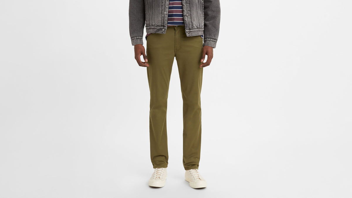Man in olive green Levi’s 511 slim jeans paired with striped tee & faded grey jacket