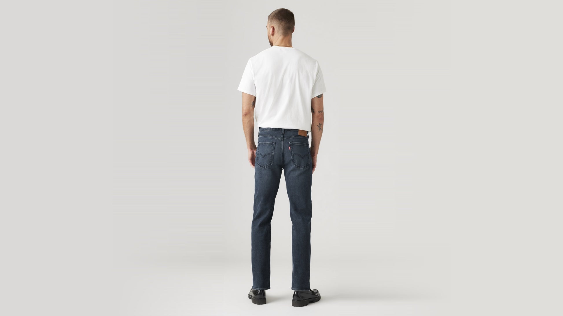 Back view of a man in dark wash Levi’s 514 jeans & a white tee, hands by his sides