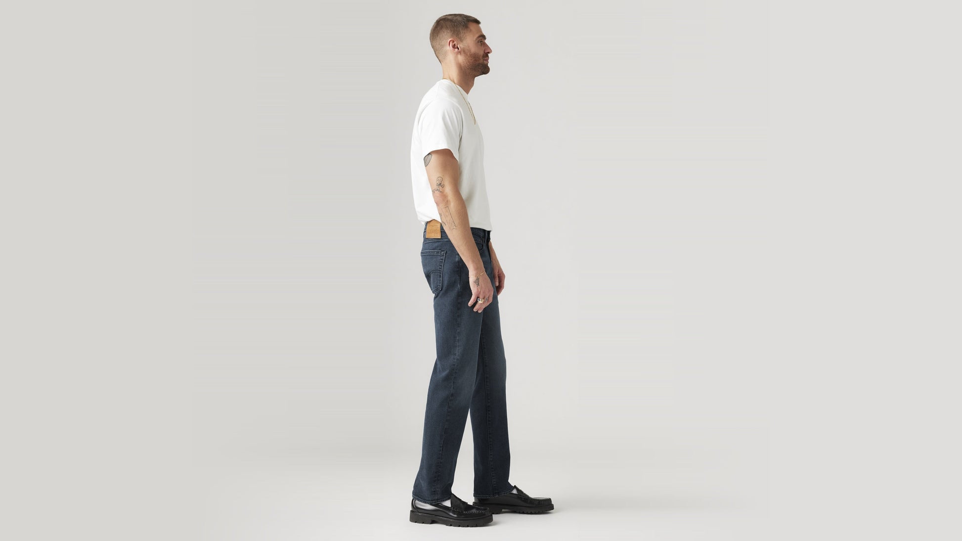 Side view of a man in dark wash straight-leg Levi’s jeans and a white tee