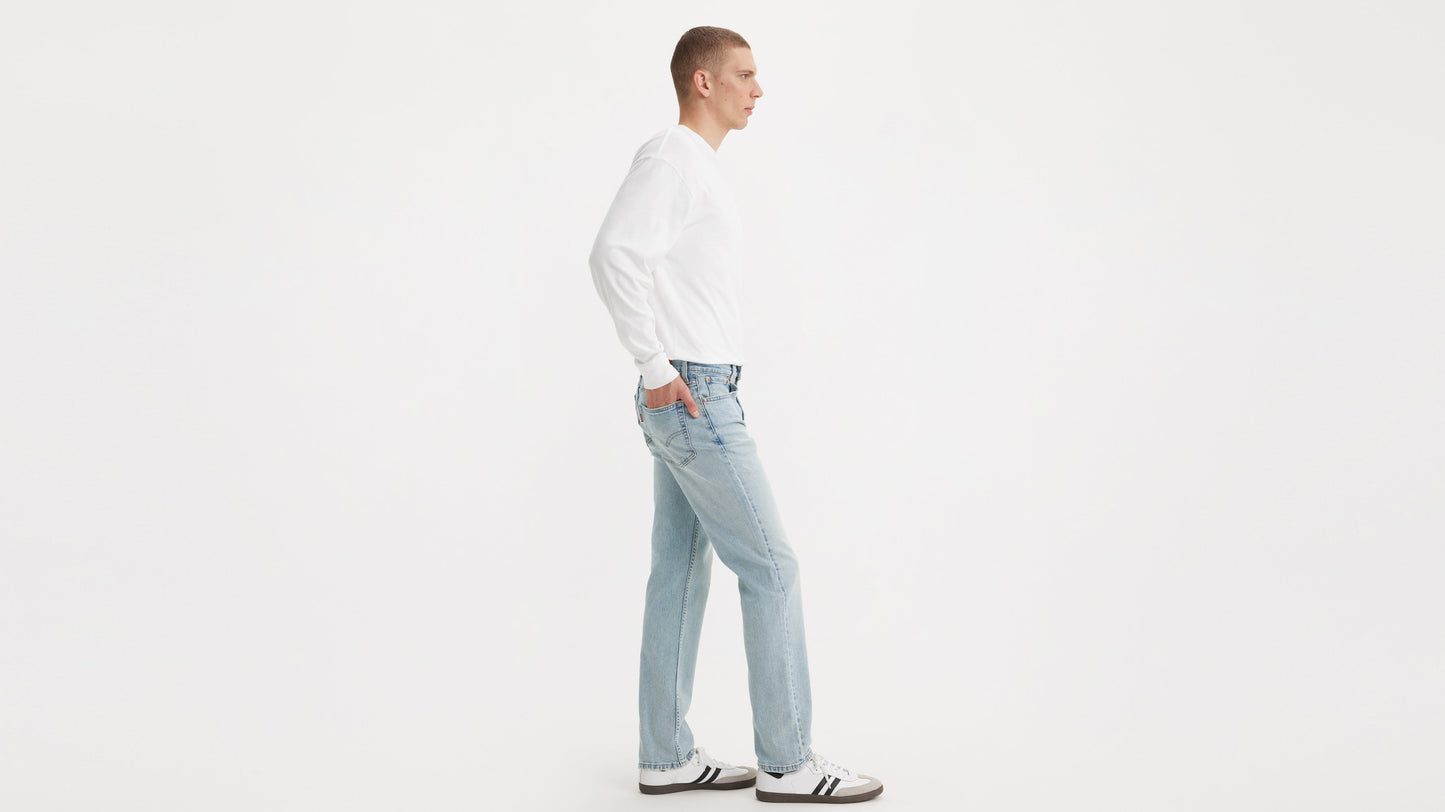 Side view of a model in Levi’s Straight jeans, white long-sleeve shirt, & sneakers