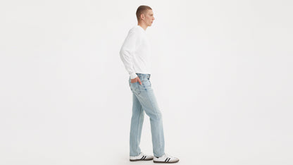 Side view of a model in Levi’s Straight jeans, white long-sleeve shirt, & sneakers